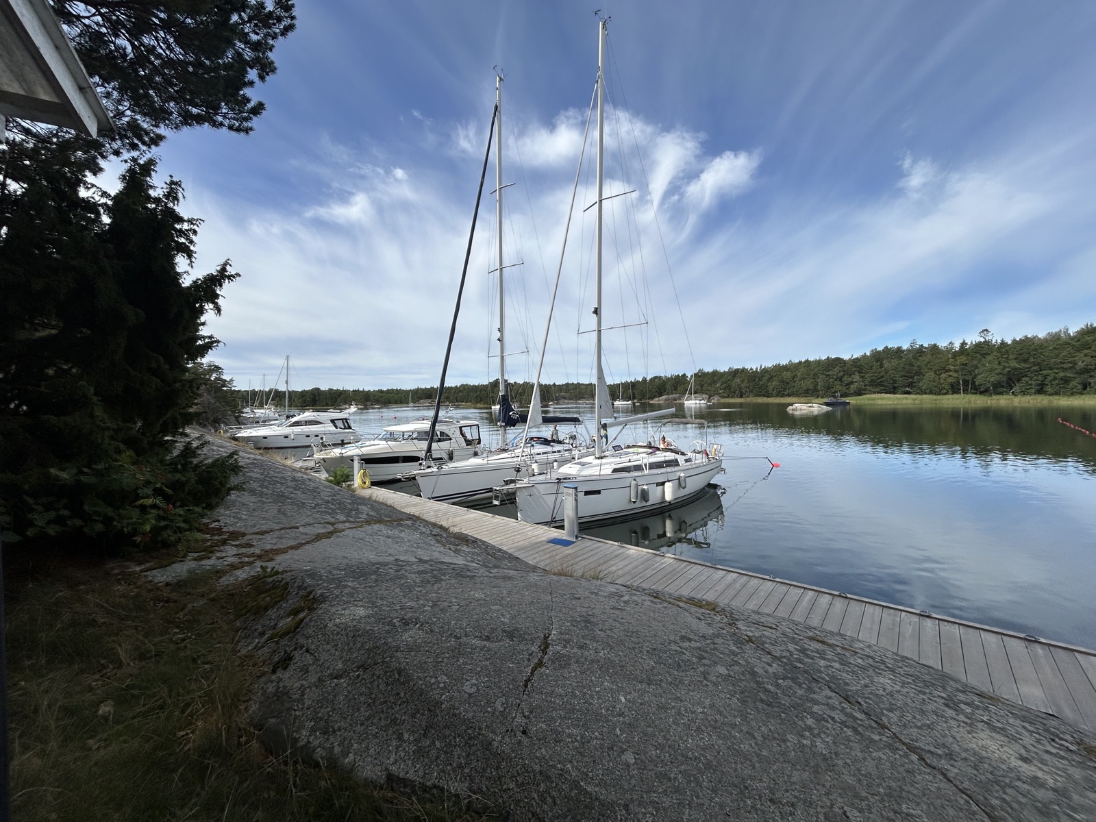 Segelbåtar med sprayhood vid brygga i Stockholms skärgård